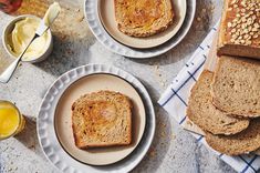 two plates with slices of bread on them next to some butter and honey syrups