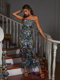 a woman is standing on the stairs in a strapless dress with flowers all over it