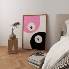 a bedroom with a bed, nightstand and art work on the wall next to it