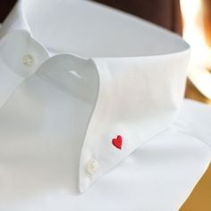 a white dress shirt with a red heart on the chest and collar, sitting on a table