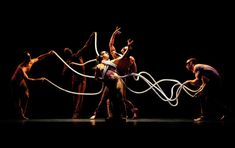 a group of people standing on top of a stage with ropes in front of them