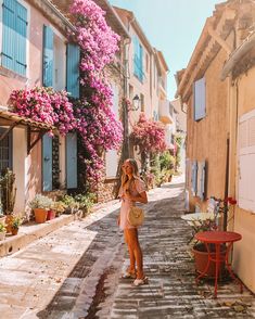 a woman standing in the middle of an alleyway with flowers growing all around her