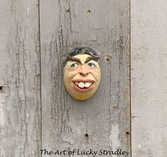 a mask on the side of a wooden wall with words above it that read, the art of lucky spradley