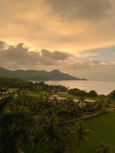 an aerial view of the golf course and ocean at sunset with palm trees in foreground