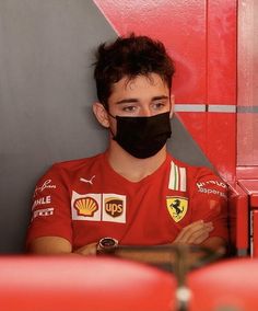 a man in a red shirt wearing a black face mask and looking at the camera