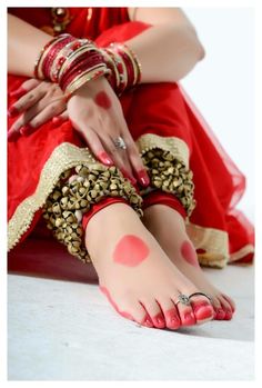 a woman in red and gold is sitting on the floor with her feet covered by polka dots