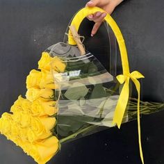 a bouquet of yellow roses is tied to a black wall with a hand holding it