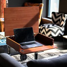 an open laptop computer sitting on top of a wooden table in front of a couch