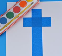 a close up of a paintbrush and paper with a cross on it