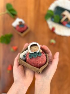 a person holding a small figurine in their hand on top of a wooden table