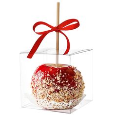 an apple with sprinkles and a red bow in a clear box on a white background