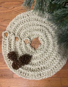 a crocheted christmas tree skirt with pine cones on the bottom and two brown buttons