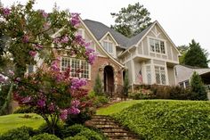 a house with stairs leading up to the front door and bushes in front of it