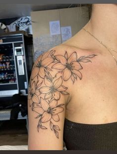 a woman with a tattoo on her shoulder has flowers in the middle of her arm