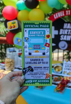 a person holding up a ticket for a game truck birthday party with balloons in the background