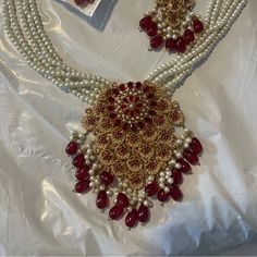 an elaborate necklace and earring set with pearls, garnets and red stones