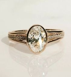 a close up of a ring on a white surface with a diamond in the center