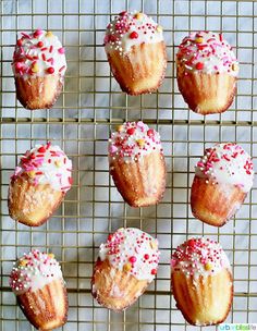 twelve cupcakes with sprinkles on a cooling rack