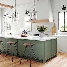 a kitchen island with stools in front of it and three hanging lights above it