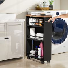 a woman is holding the door open to a washer and dryer in a room