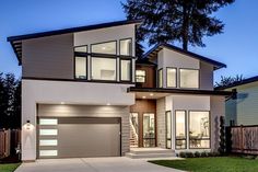 a modern home at night with large windows and two car garages on the front