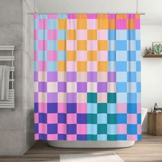 a bathroom with a shower curtain that has colorful squares on it and a rug in the corner