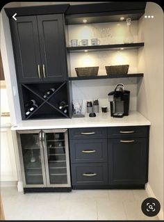 a kitchen with black cabinets and white counter tops, wine glasses on the shelves above