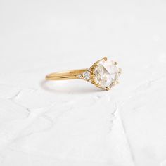 a gold ring with an oval cut diamond and two small round diamonds on the side