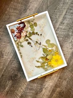 a painting with flowers and leaves in it on a wooden table next to a paintbrush