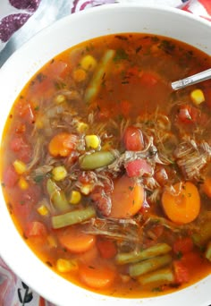 a white bowl filled with vegetable soup on top of a red and white table cloth