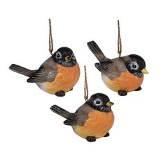 three small birds hanging from strings on a white background, one is orange and the other is black