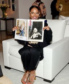 a woman sitting on a white couch holding up pictures