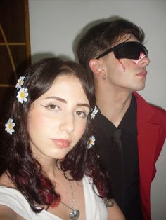 two people with fake flowers in their hair and one person wearing sunglasses looking at the camera