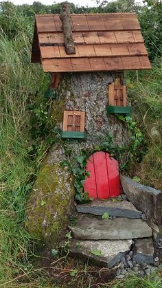 a small tree house with a red door and window on the side of a rock