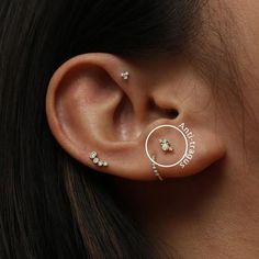 a woman's ear with three different piercings on her left side and two smaller ones in the middle