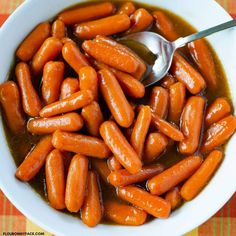 a bowl filled with carrots and sauce on top of a checkered table cloth