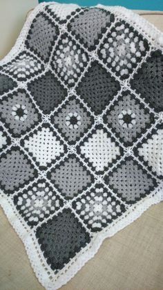 a black and white crocheted blanket sitting on top of a couch