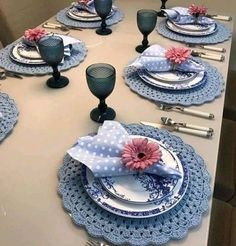 the table is set with blue and white plates, silverware, and pink flowers