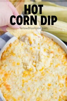 a hand dipping corn into a white bowl filled with cheesy dip and topped with tortilla chips