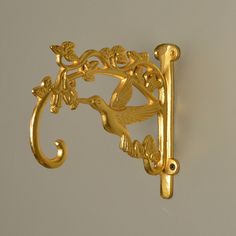 an ornate gold hook with a bird on it's side and leaves in the middle