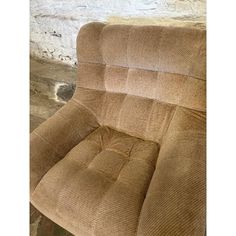 a brown reclining chair sitting on top of a wooden floor next to a brick wall