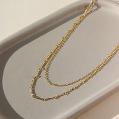 a 14k gold fill necklace made up of two chains, laid out on a sunny table Affordable Everyday Double Strand Chain Necklace, Minimalist Multi-strand Clavicle Chain Necklace, Everyday Multi-strand Double Chain Necklace, Modern Double Strand Necklace With Delicate Chain, Dainty Multi-strand Chain Necklace For Layering, Minimalist Multi-strand Layered Chain Necklace, Minimalist Multi-strand Chain Necklace, Modern Delicate Chain Layered Necklace, Multi-strand Paperclip Chain Necklace