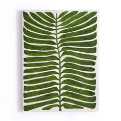 a large green leaf on a white wall hanging from the side of a wooden frame