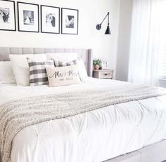 Above this king-size bed hangs a gallery wall of black and white wedding photographs that extends the width of the bed, framed by black lamp sconces on both sides. A farmhouse touch is integrated with the distressed nightstands on both sides of the bed and the gingham print throw pillows that rest on a white comforter...   Image: moseleyfamfarmhouse