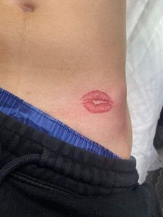 a close up of a person's stomach with a red lip tattoo on it