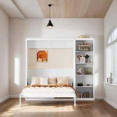 a white bed sitting under a window next to a book shelf