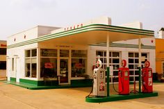 an old gas station with two red and green pumps