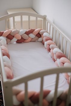 a baby crib with pink and white pillows on it