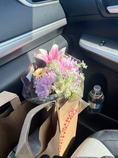 a bouquet of flowers sitting in the passenger seat of a car, next to a paper bag