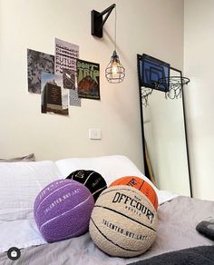 three basketballs sitting on top of a bed next to a mirror